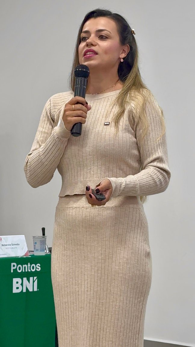 Amanda Simeão falando ao microfone em evento empresarial
