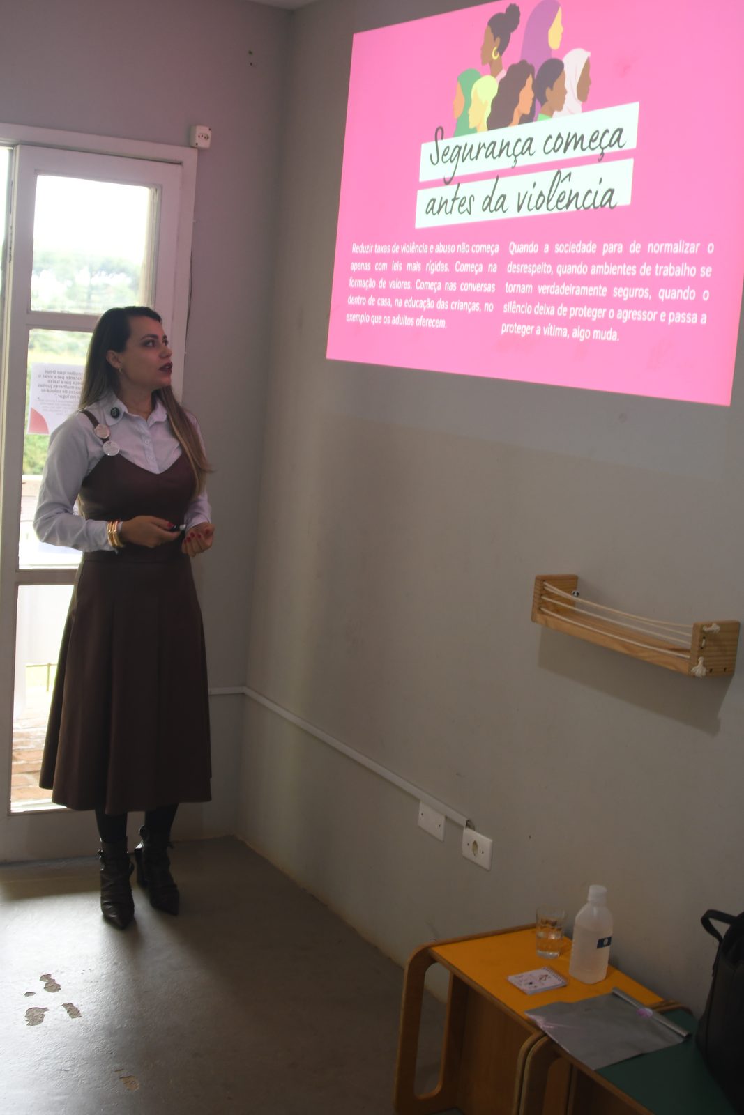 Amanda Simeão de corpo inteiro apresentando ao lado da projeção